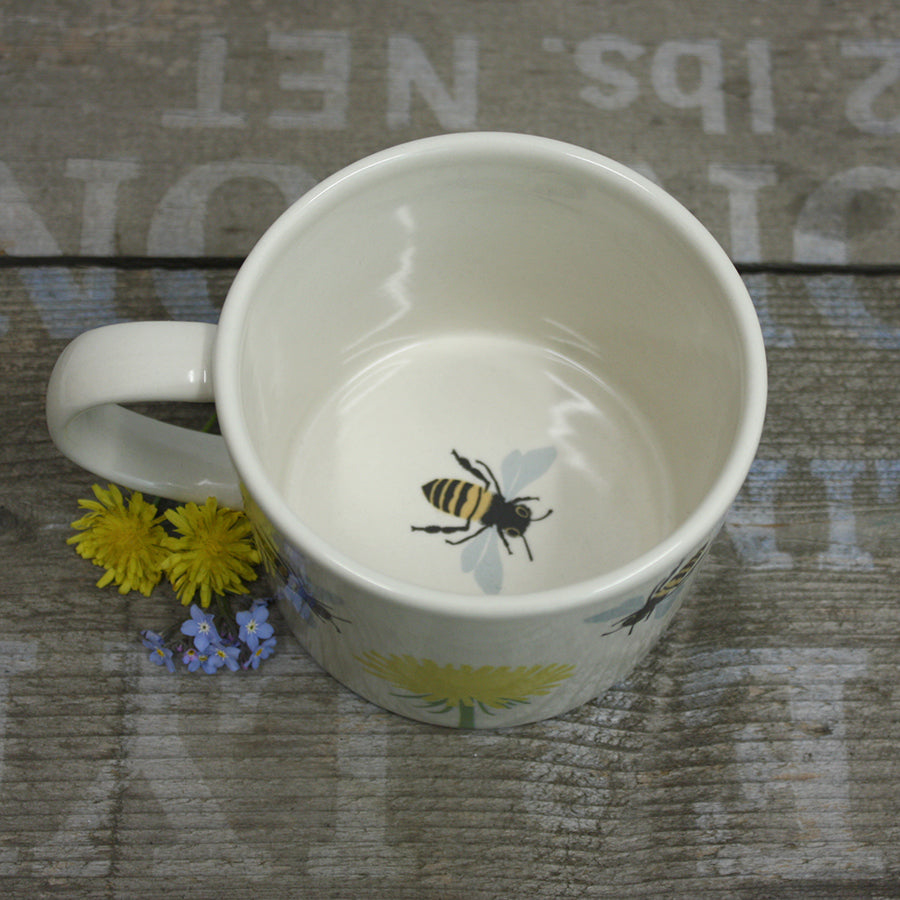 White mug with bee design on a textured surface