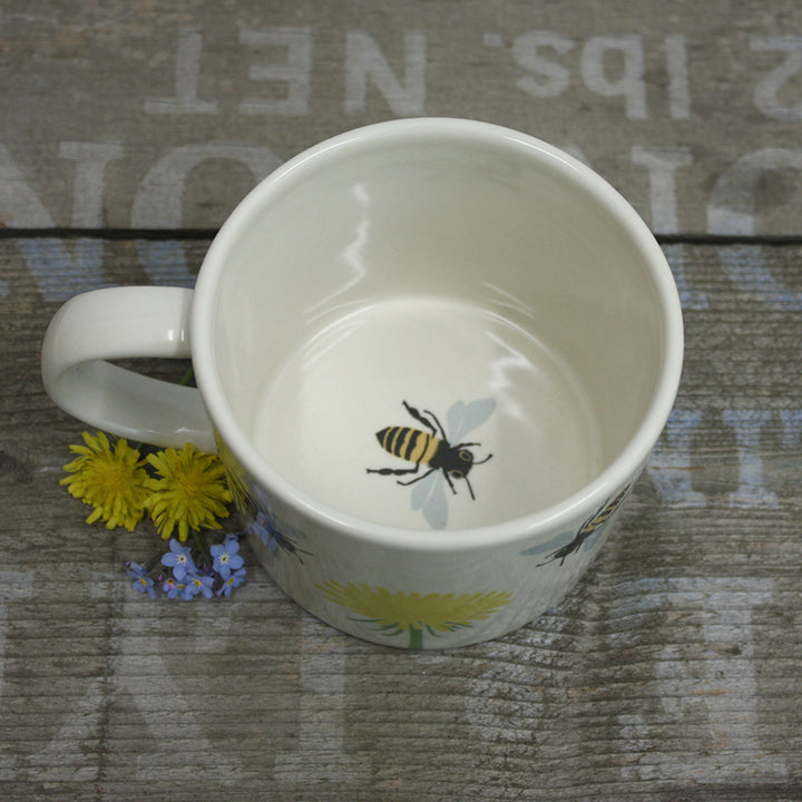 White mug with bee design on a textured surface