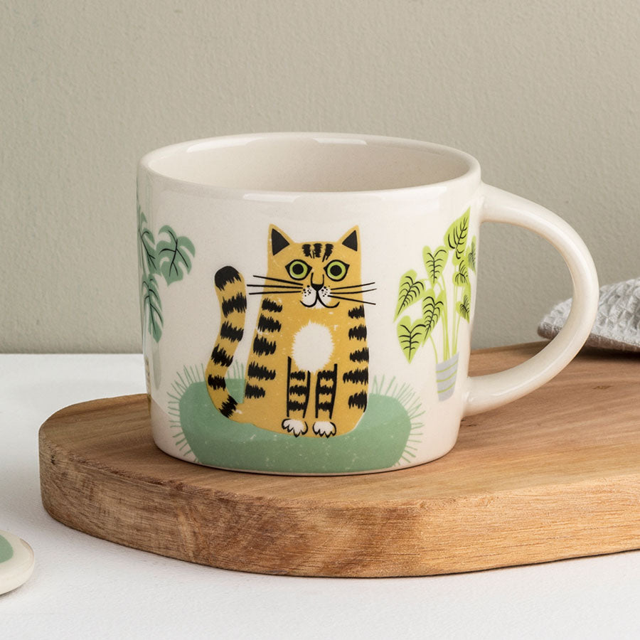 White mug with a cat illustration on a wooden coaster