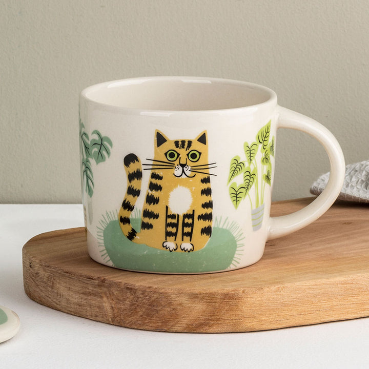 White mug with a cat illustration on a wooden coaster