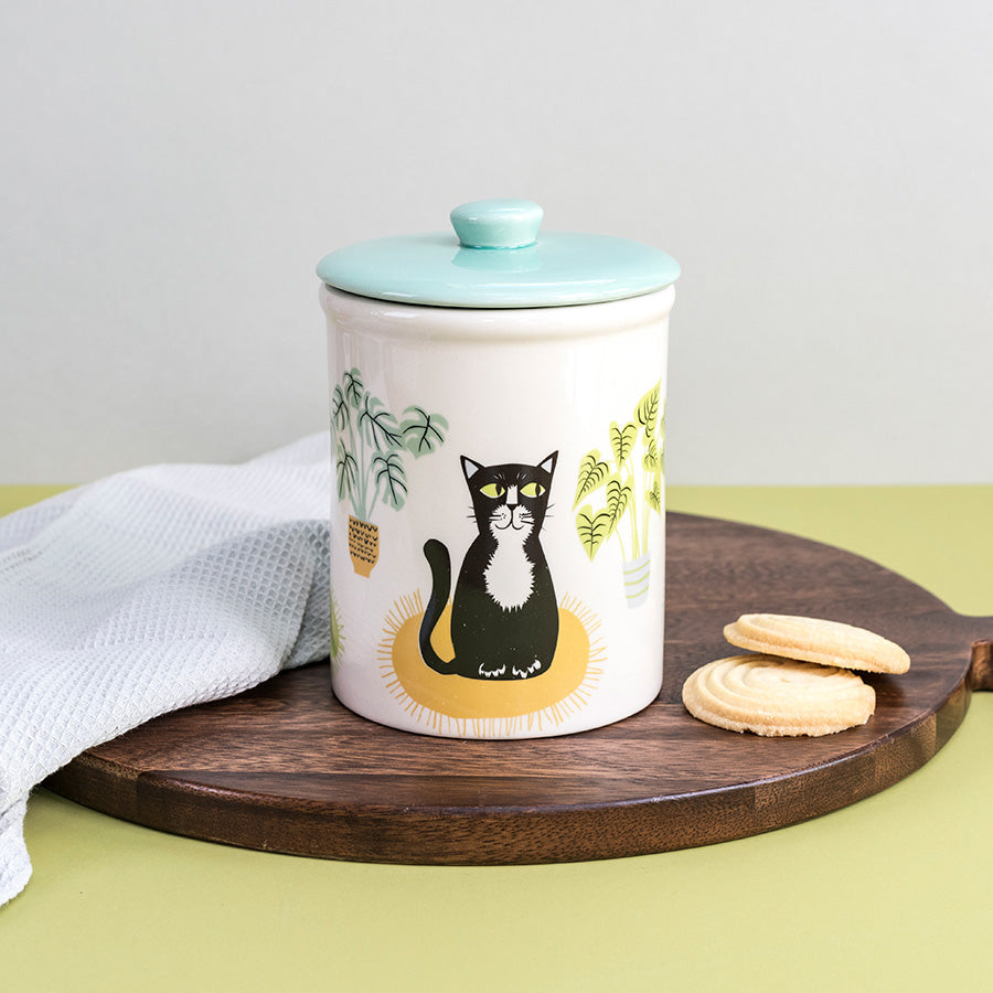 Ceramic storage  jar with a cat design on a wooden board with cookies