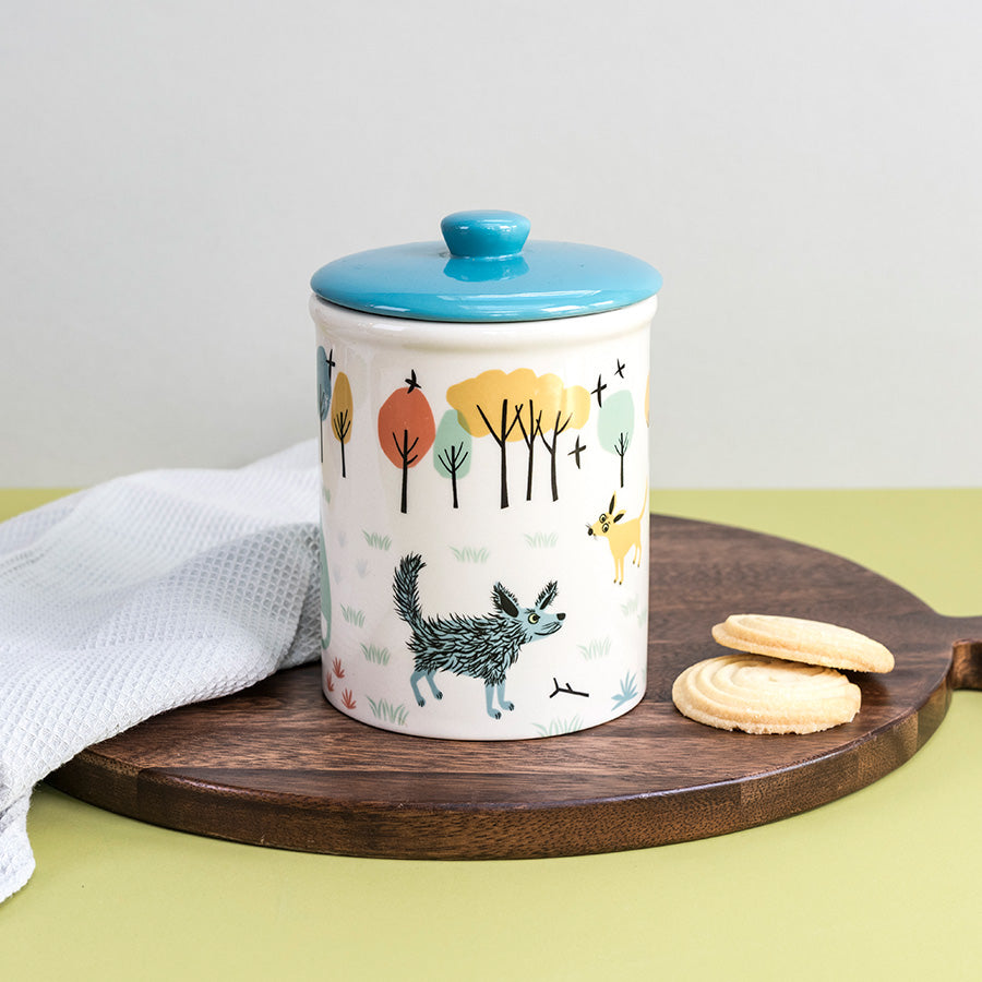 Storage jar with dog illustrations on a wooden board with cookies