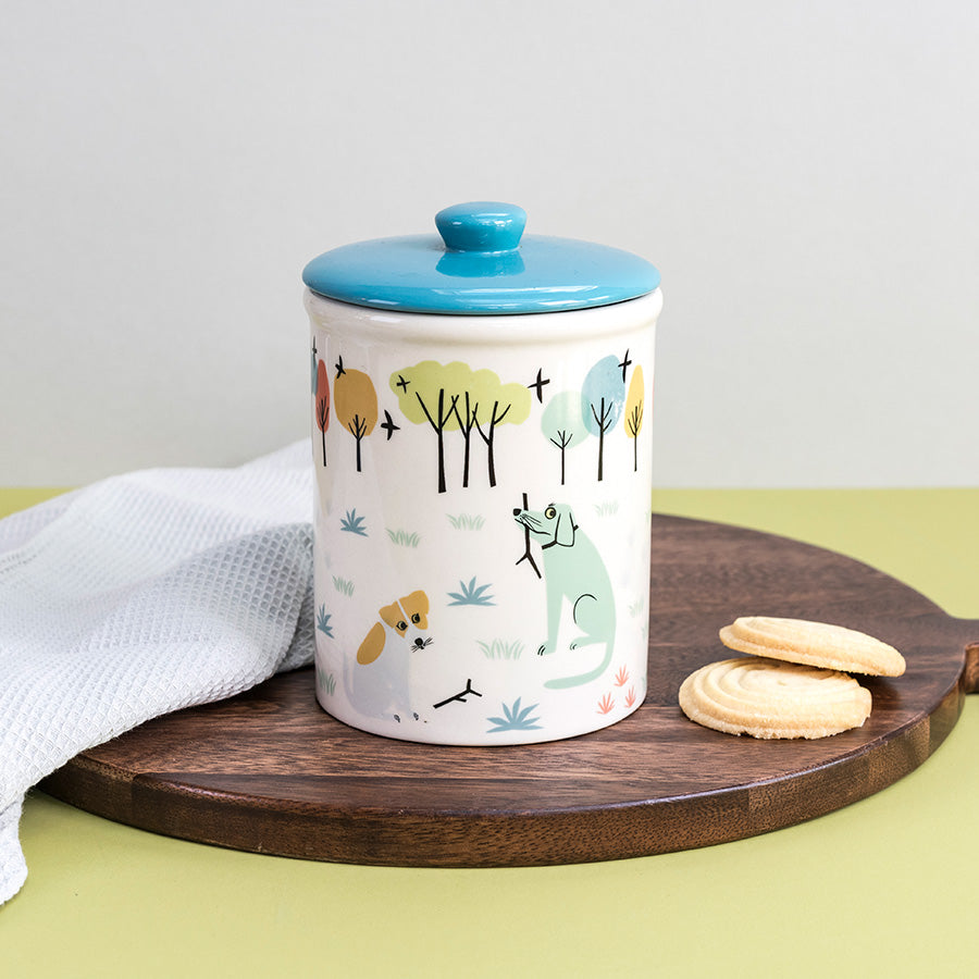 Ceramic Storage jar with a blue lid on a wooden board with cookies, against a light gray background.