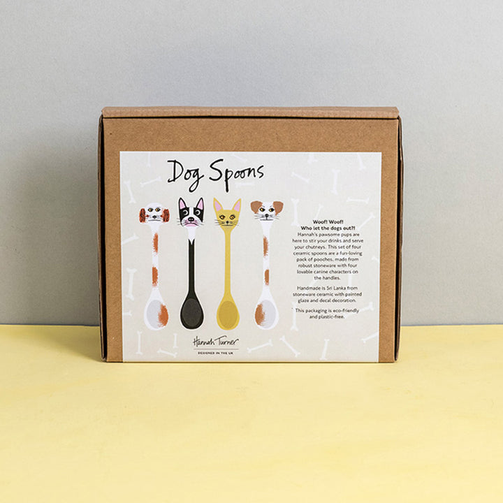 Brown cardboard box of Dog Spoons with illustration on a light grey background with the text 'Hannah Turner designed in the UK'. Packaging shot for Hannah Turner's Ceramic Dog Spoon Set.
