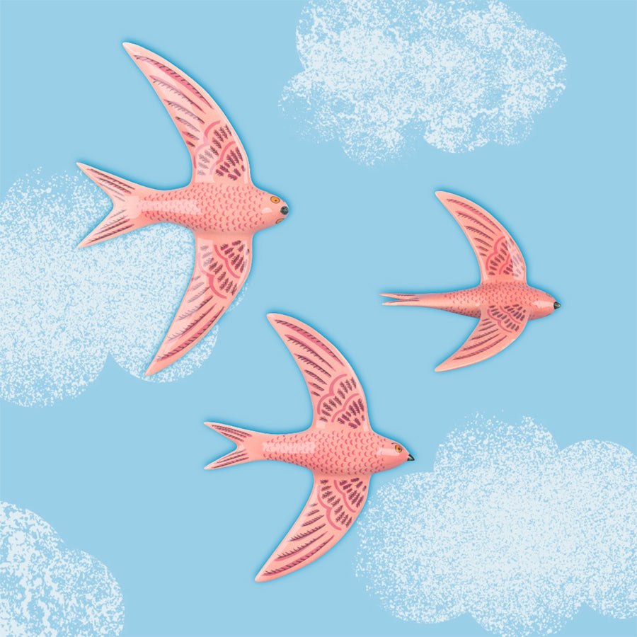 3 pink ceramic swifts by Hannah Turner flying on a blue sky.
