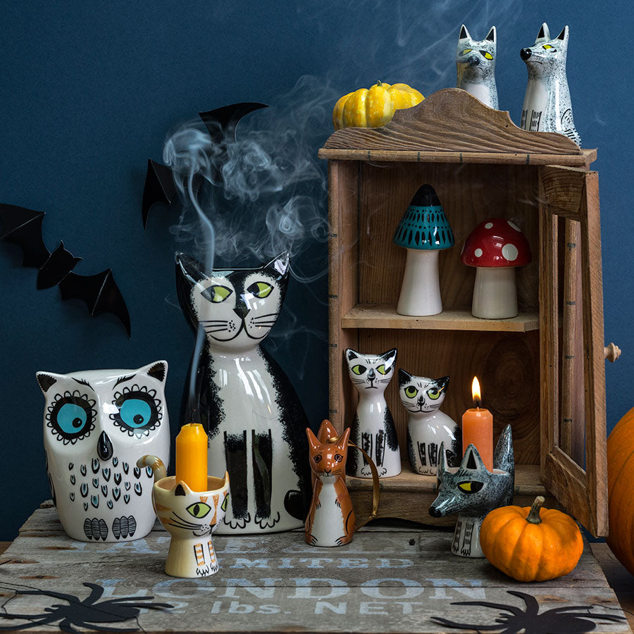 Halloween-themed decor with ceramic cats, owls, and mushrooms on a table.