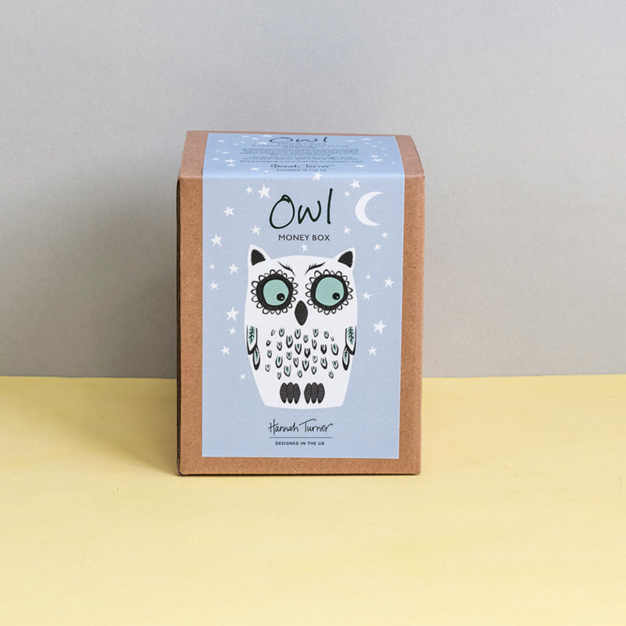 Brown kraft gift box with owl design on a grey stars background printed with text 'Hannah Turner designed in the UK'. Packaging for Hannah Turner's Ceramic Owl Money Box.