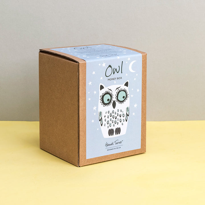 Brown kraft gift box with owl design on a grey stars background printed with text 'Hannah Turner designed in the UK'. Packaging for Hannah Turner's Ceramic Owl Money Box.