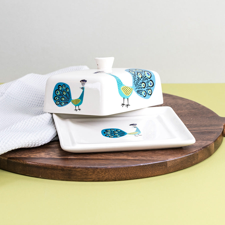 White ceramic dish set with peacock design on a wooden board