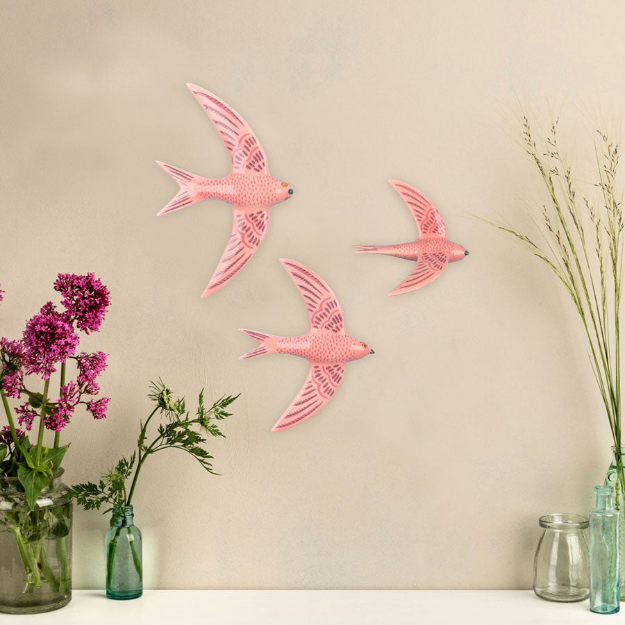 3 Pink Flying swifts on a plain background, flowers and grasses at the edge. 