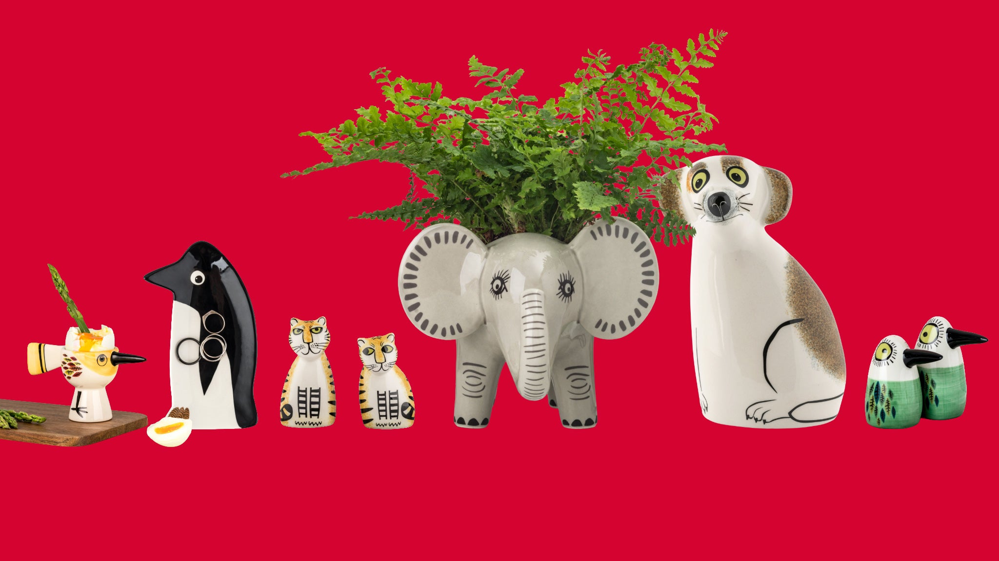 A promotional banner featuring a collection of ceramic animal salt & pepper shakers, trinket dishes, egg cups and planters on a solid red background, including a grey elephant planter with green ferns . A white circular sticker in the top left reads '20% OFF' with the website www.