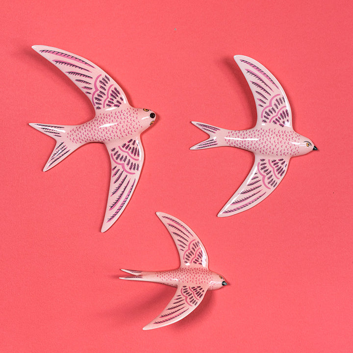 Three pink flying swifts on a pink background