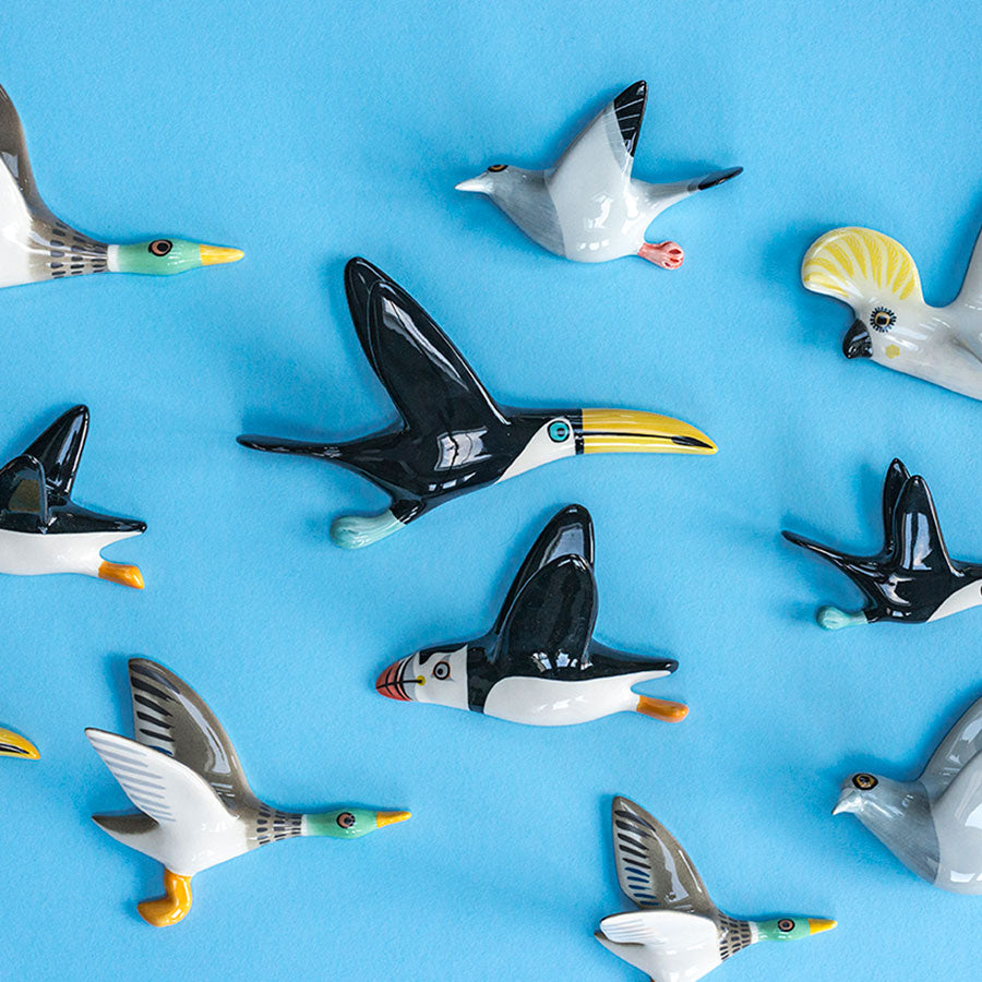 Collection of ceramic bird wall ornaments on a blue background