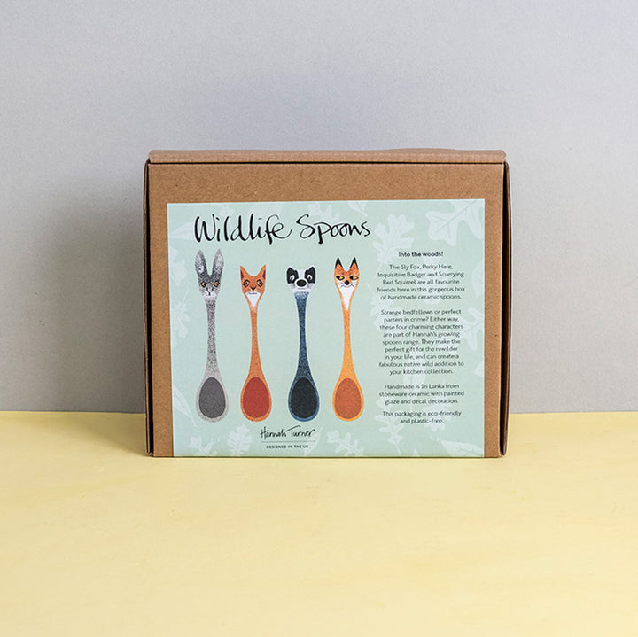 Brown cardboard box of Wildlife Spoons with illustration on a light grey background with the text 'Hannah Turner designed in the UK'. Packaging shot for Hannah Turner's Ceramic Wildlife Spoon Set.