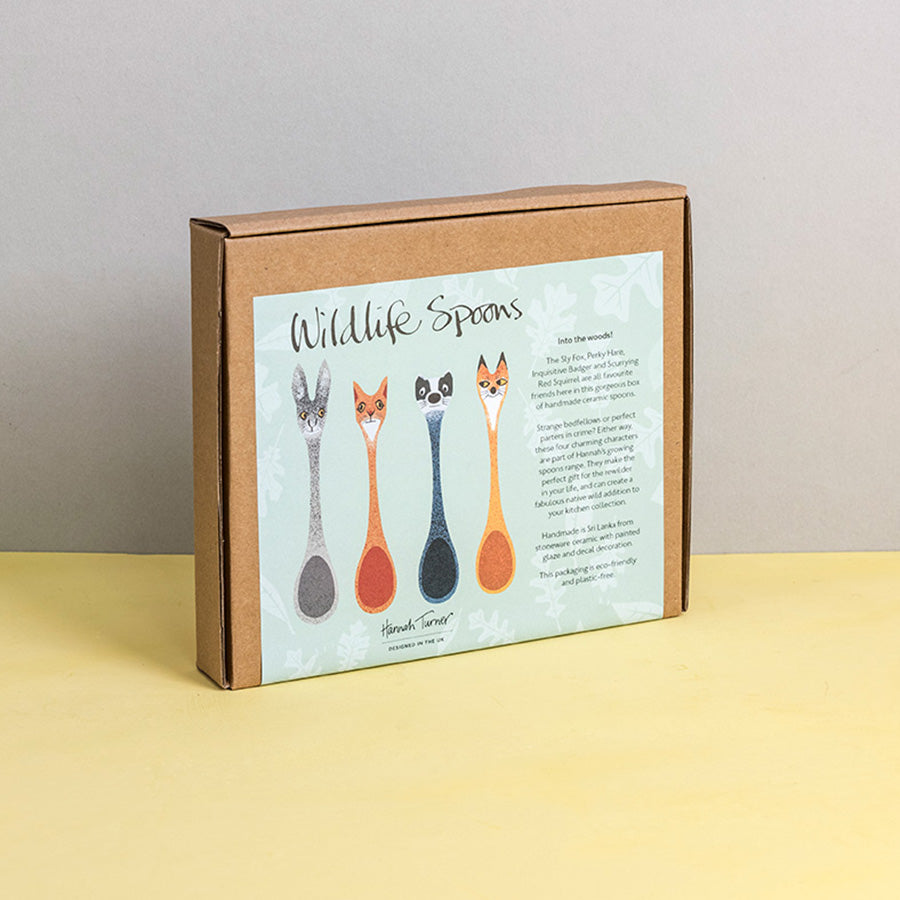 Brown cardboard box of Wildlife Spoons with illustration on a light grey background with the text 'Hannah Turner designed in the UK'. Packaging shot for Hannah Turner's Ceramic Wildlife Spoon Set.