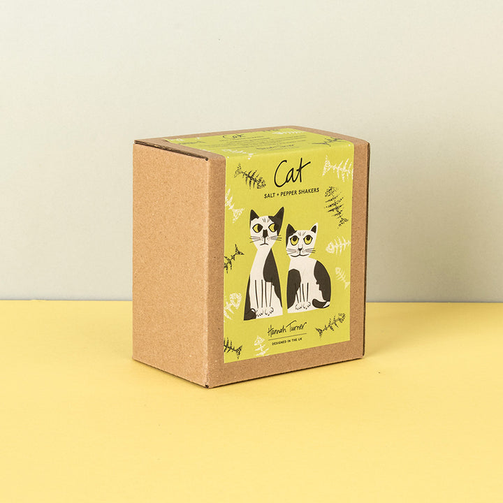 A square kraft paper box for black and white cat salt and pepper shakers, featuring a yellow-green label with illustrations of two cats and the text 'Cat Salt & Pepper Shakers'.
